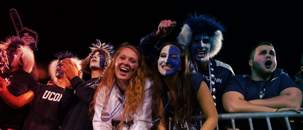 a group of UConn athletic fans are in face paint and celebrating