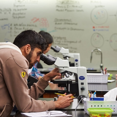 student looks through high-powered microscope in lab