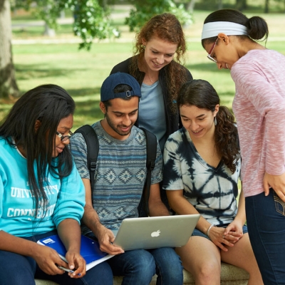 students at harford campus walkway gather around for a presentation on a laptop