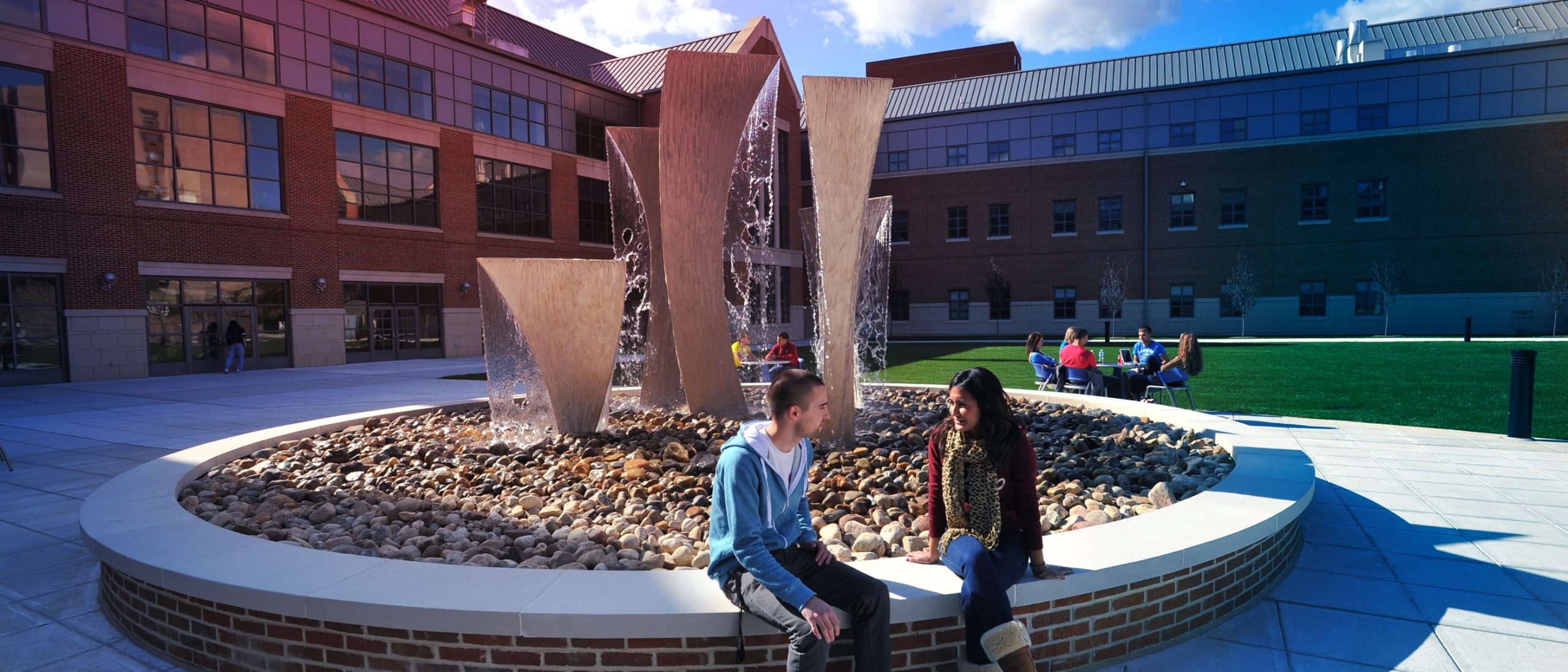 students sit near statuary in UConn Waterbury campus