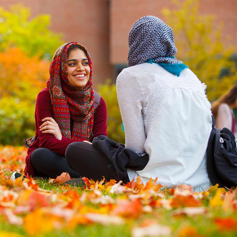 57 of 98151022d241 2.JPG Sitting and talking on a fall day outside at the Student Union Mall with leaves on the ground