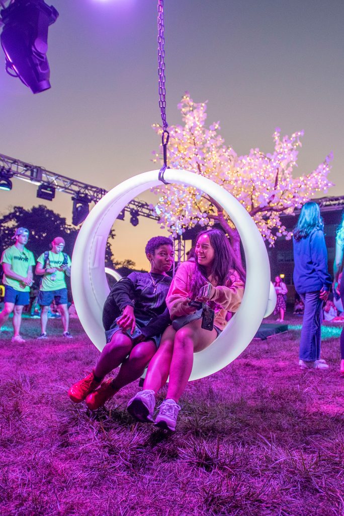 students sit on the glowing swings from convocation event