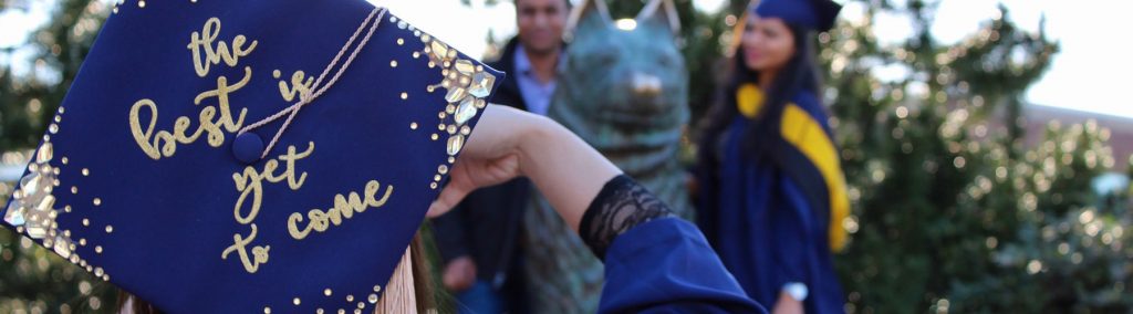 a student poses infront of the UConn Jonathan statue while wearing a graduate cap bedazzled with the phrase, the best is yet to come