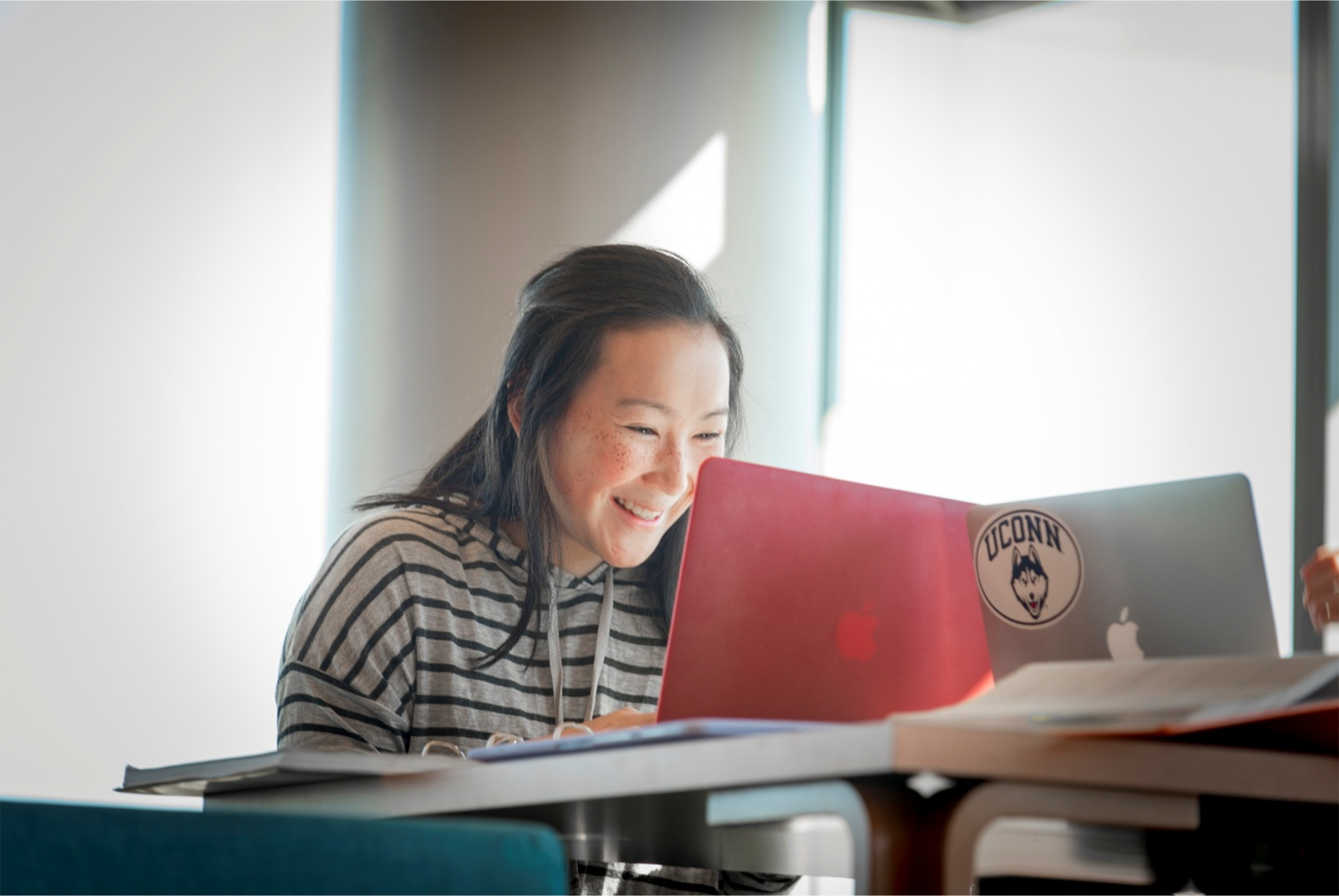 A student smiles as she works on her laptop.